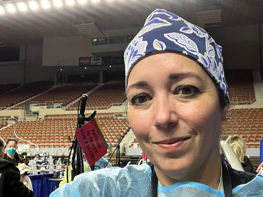 dental hygienist in scrubs poses for photo while volunteering at a community event